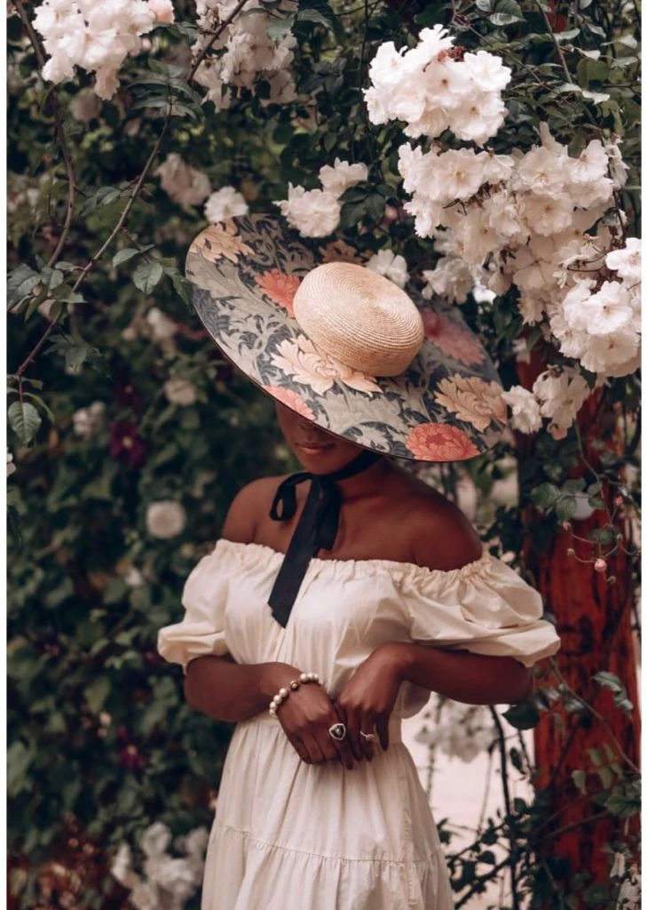 Woman in white dress with floral hat among garden roses