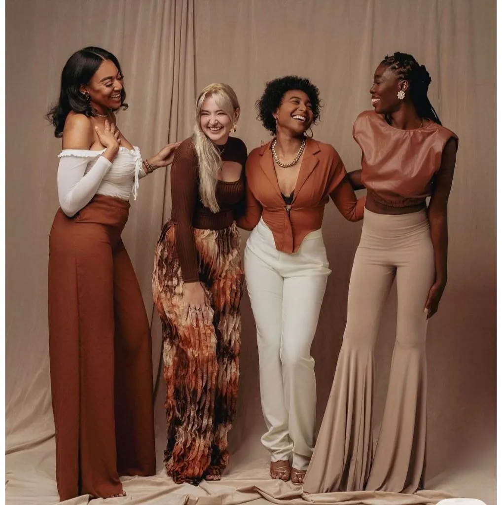 Four women laughing in coordinated earth-tone outfits